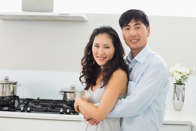 Young man embracing woman from behind in kitchen