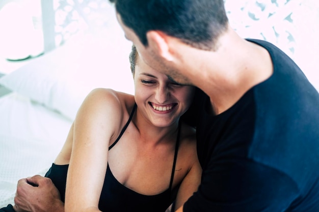Photo young man embracing woman while sitting on bed at home