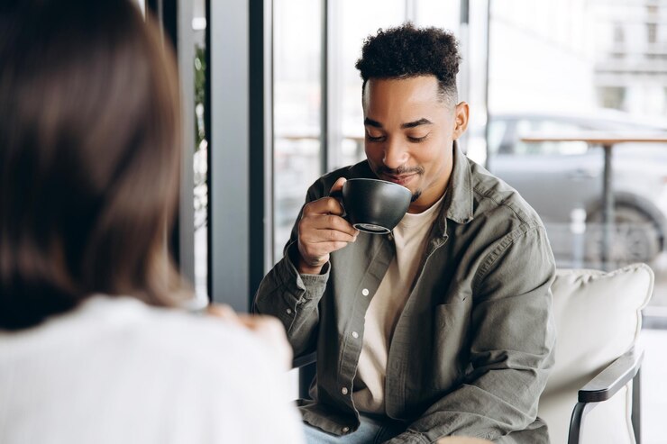 Photo young man enjoying a cup of coffee during a casual meeting at a cafe