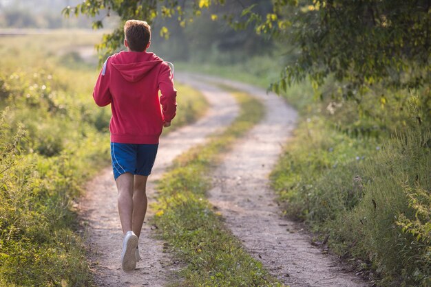 young man enjoying in a healthy lifestyle while jogging along a country road, exercise and fitness concept