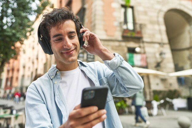 Young man enjoys the convenience of mobile music wearing headphones and carrying his smartphone