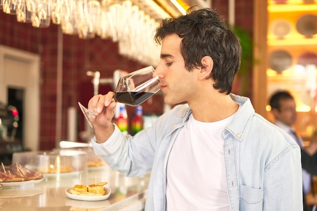 Young man enjoys wine tasting at bar counter