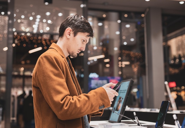 A young man examines a smartphone in a store