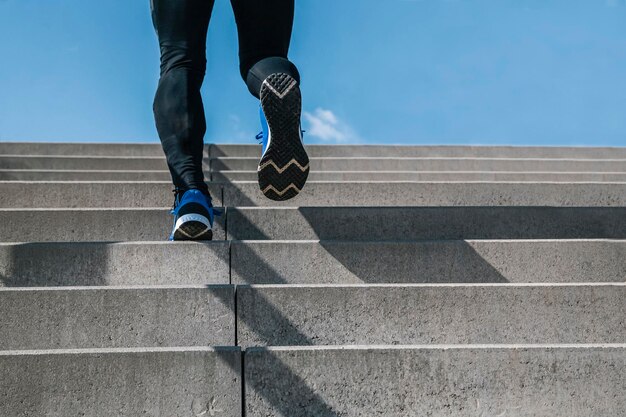 Photo young man exercising climbs stairs outdoors cut the view of strong and powerful legs