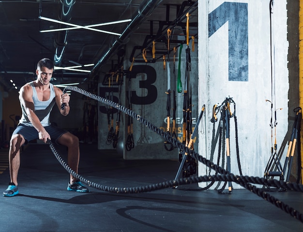 Photo young man exercising with battle ropes