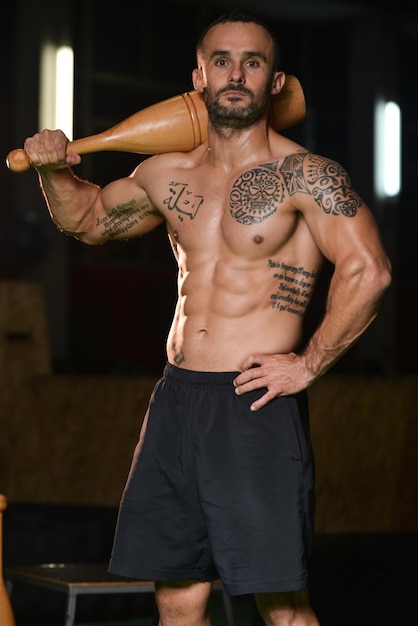 Young Man Exercising With Bowling Pin And Flexing Muscles  Muscular Athletic Bodybuilder Fitness Model Exercises