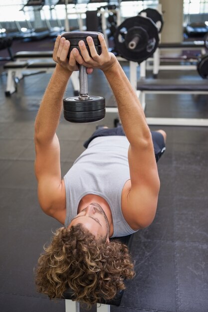 Photo young man exercising with dumbbell in gym