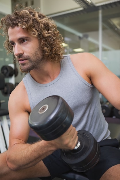 Young man exercising with dumbbell in gym