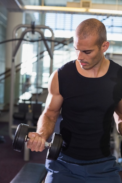 Young man exercising with dumbbells in gym