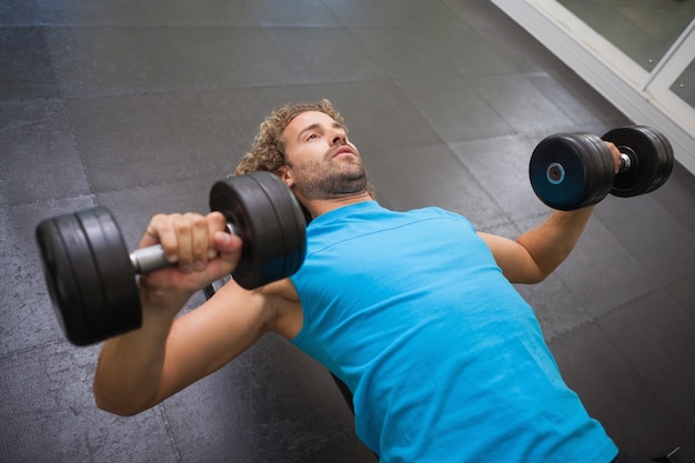 Photo young man exercising with dumbbells in gym