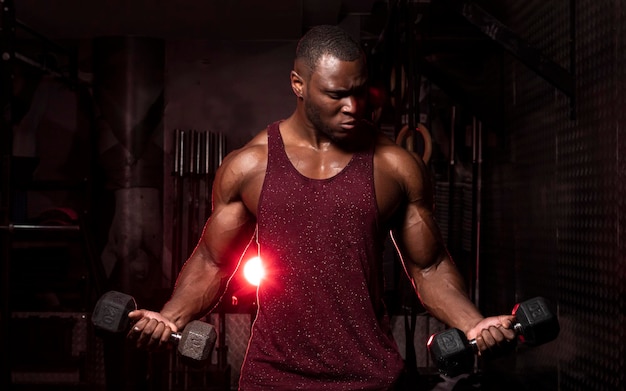 young man exercising with dumbbells while standing in gym