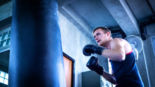 Photo young man exercising with punching bag in gym