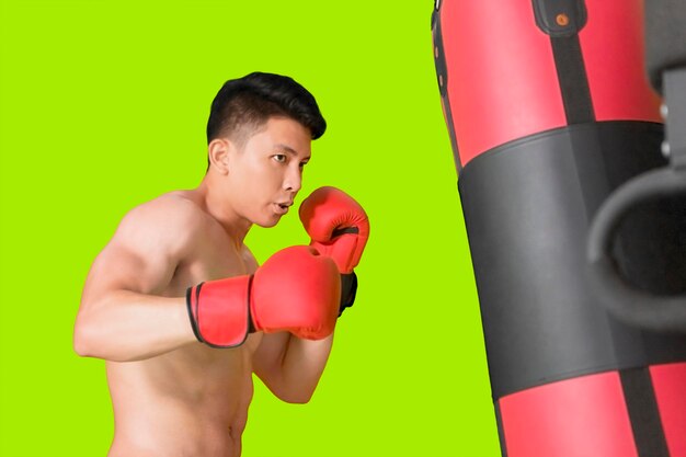 Young man exercising with punching bag on studio