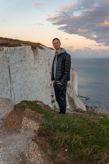 Young man exploring the White Cliffs of Dover in UK. Sitting on top of the cliff watching English canal.