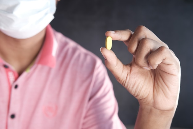 Young man in face mask holding medical pills