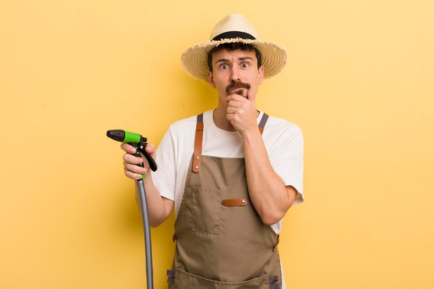 Young man farmer with a hose gardering concept