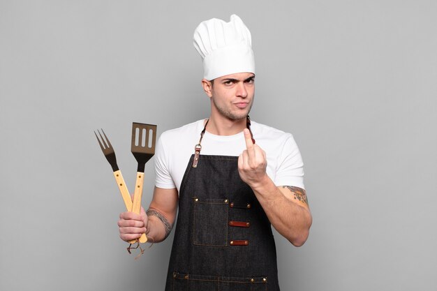 Young man feeling angry, annoyed, rebellious and aggressive, flipping the middle finger, fighting back