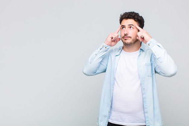 Young man feeling confused or doubting, concentrating on an idea, thinking hard, looking to copy space on side