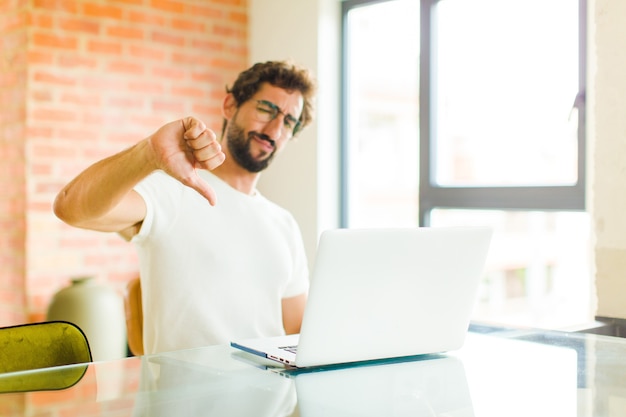 Young man feeling cross, angry, annoyed, disappointed or displeased, showing thumbs down with a serious look