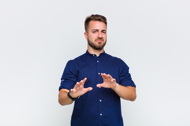 Young man feeling disgusted and nauseous, backing away from something nasty, smelly or stinky, saying yuck