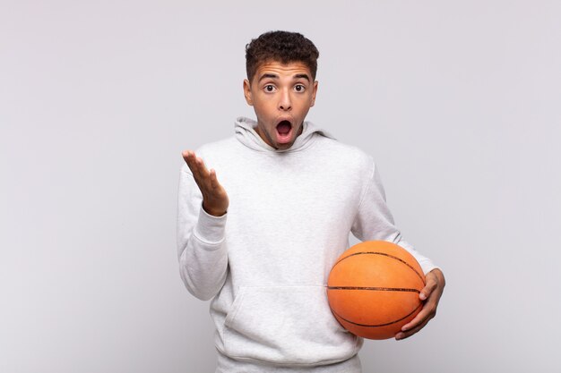 Young man feeling extremely shocked and surprised, anxious and panicking, with a stressed and horrified look. basket concept