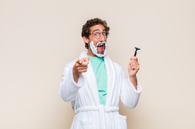 Young man feeling happy and confident, pointing to front with both hands and laughing, choosing you