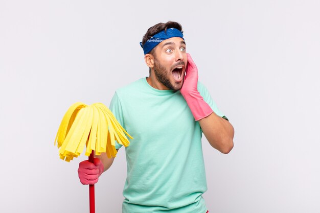 Young man feeling happy, excited and surprised, looking to the side with both hands on face