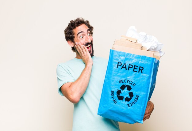 Young man feeling happy, excited and surprised, looking to the side with both hands on face