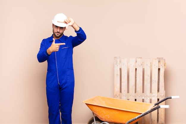 Young man feeling happy, friendly and positive, smiling and making a portrait or photo frame with hands construction concept