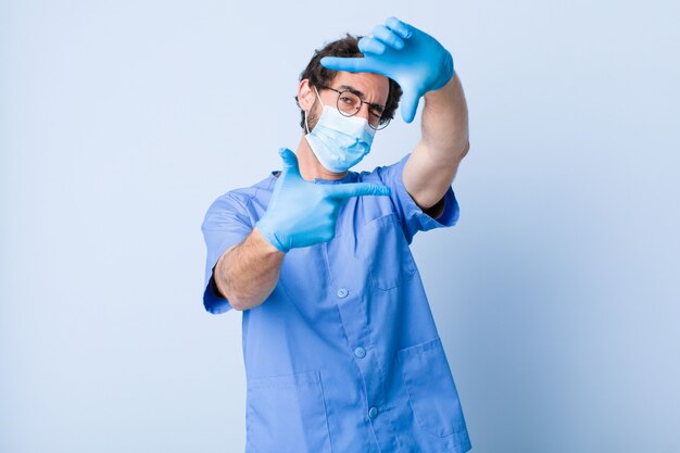 Young man feeling happy, friendly and positive, smiling and making a portrait or photo frame with hands. coronavirus concept