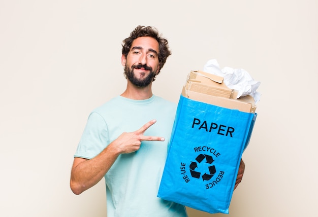 Young man feeling happy, positive and successful, with hand making v shape over chest, showing victory or peace