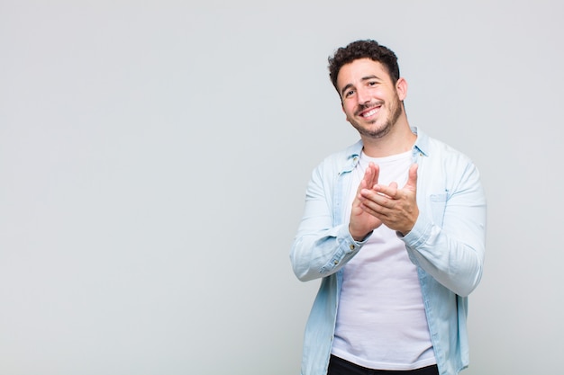 Young man feeling happy and successful, smiling and clapping hands, saying congratulations with an applause