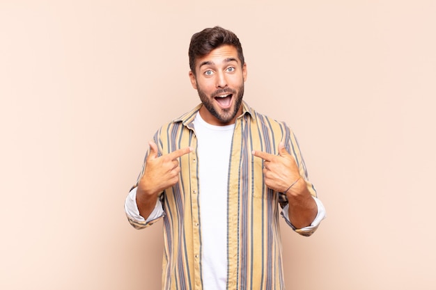 Young man feeling happy, surprised and proud, pointing to self isolated