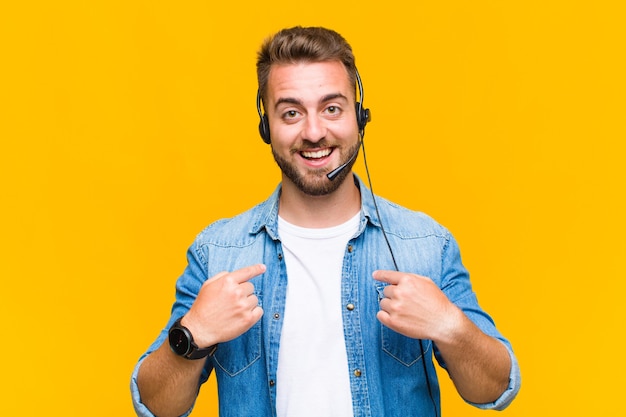 Young man feeling happy, surprised and proud, pointing to self with an excited, amazed look