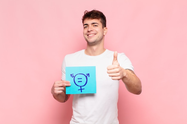 Young man feeling proud, carefree, confident and happy, smiling positively with thumbs up