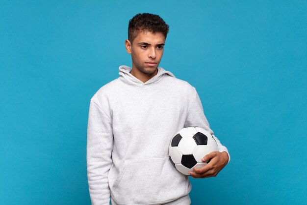 Young man feeling sad, upset or angry and looking to the side\
with a negative attitude, frowning in disagreement. soccer\
concept