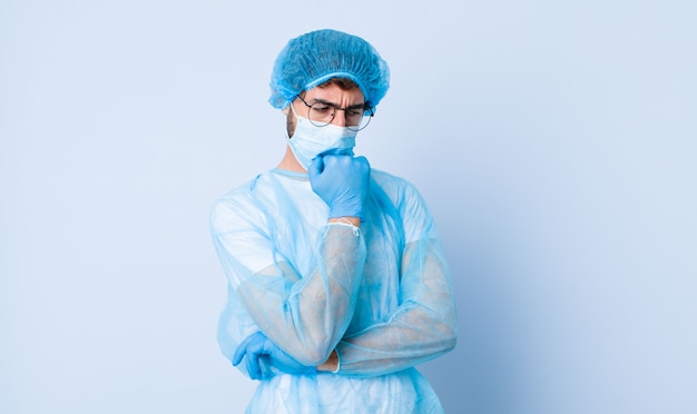 Young man feeling serious, thoughtful and concerned, staring sideways with hand pressed against chin. coronavirus concept