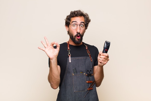 Young man feeling shocked, amazed and surprised, showing approval making okay sign with both hands