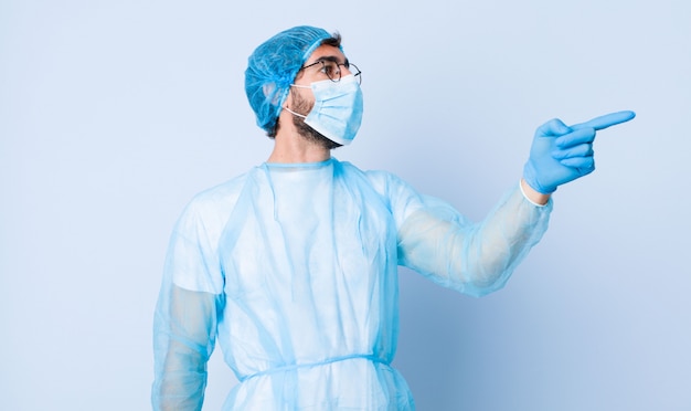 Young man feeling shocked and surprised, pointing and looking upwards in awe with amazed, open-mouthed look. coronavirus concept