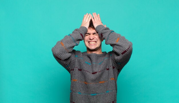 Young man feeling stressed and anxious, depressed and frustrated with a headache, raising both hands to head