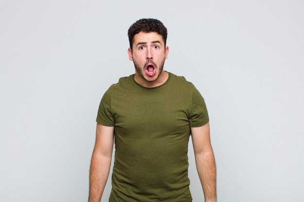 Young man feeling terrified and shocked, with mouth wide open in surprise