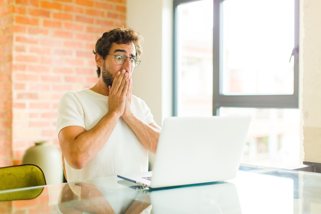 Young man feeling worried, upset and scared, covering mouth with hands, looking anxious and having messed up