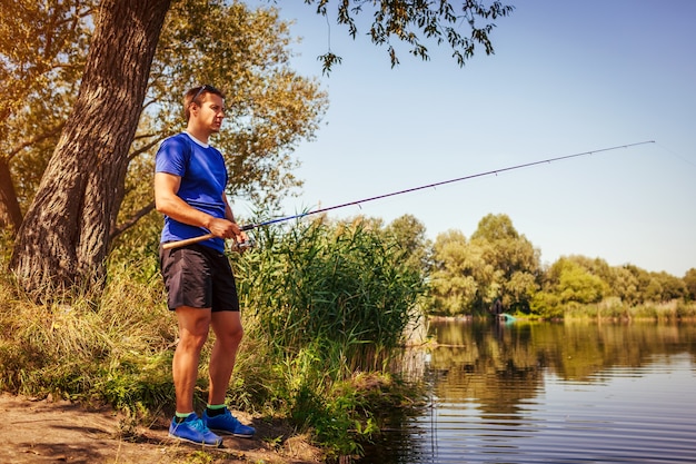 Молодой человек, ловящий рыбу на берегу реки