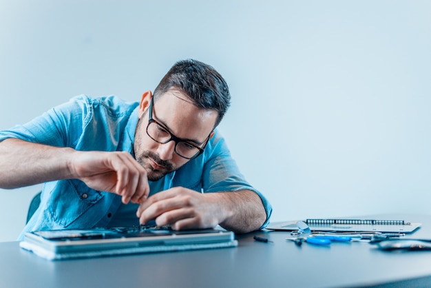 Young man fixing a broken laptop.