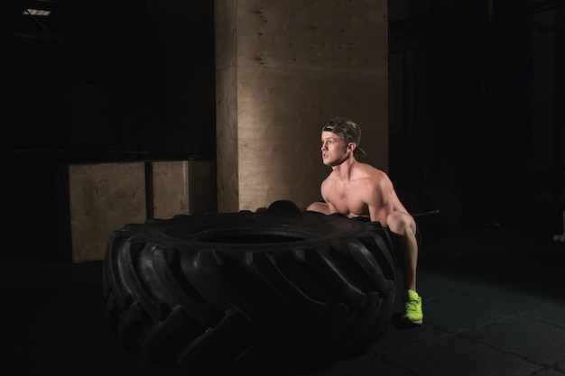 Young man flipping tire at gym