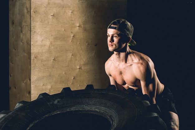 Young man flipping tire at gym