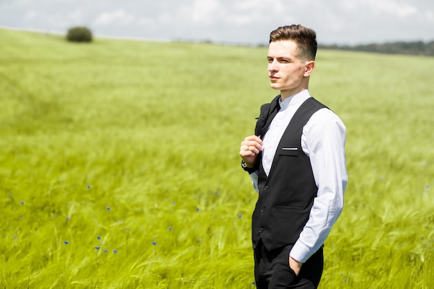 Young man in formal suit on the green field