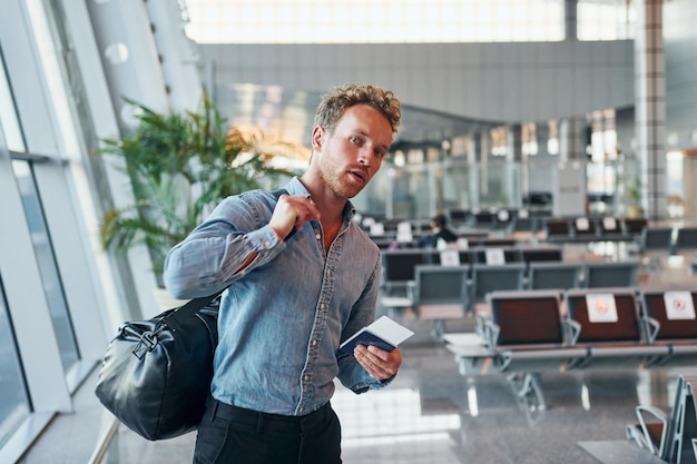 Young man in formal wear is in modern airport Conception of vacation