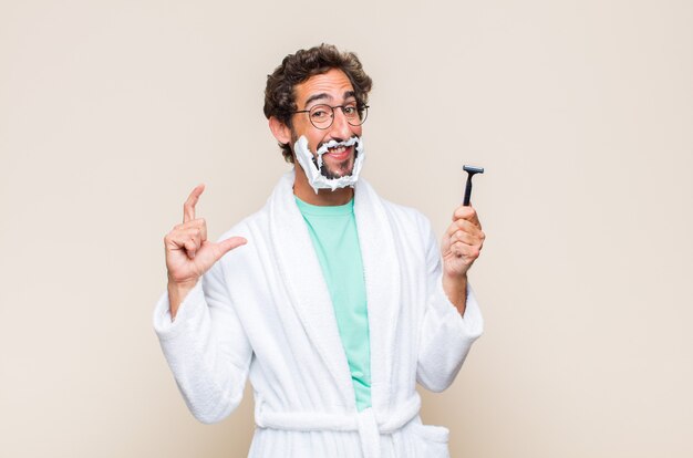 Young man framing or outlining own smile with both hands, looking positive and happy, wellness concept