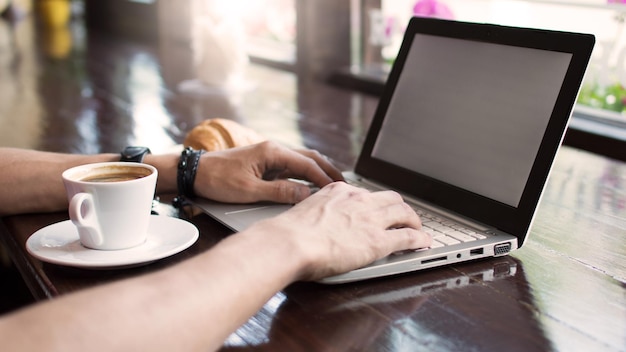 Young man freelancer working from a cafe with a laptop hipster\
guy using modern laptop computer while working in a vintage loft\
closeup of male hands